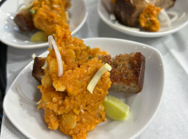 Gelber Erbsenhummus mit geröstetem Landbrot und Olivenöl angerichtet auf einem Teller.