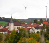Dorf mit Kirche im Grünen mit Windrädern © Oliver Schikora