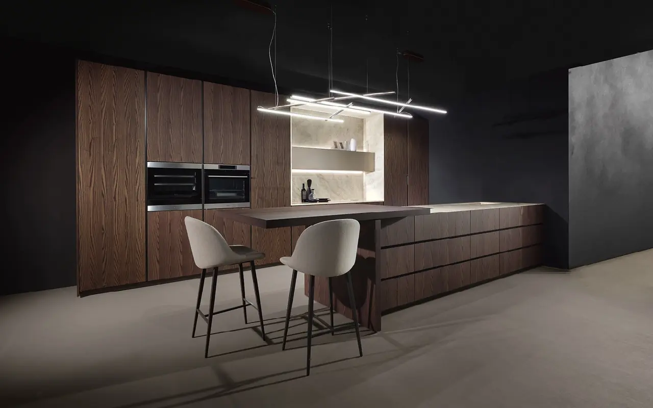 Koyu ahşap dolaplı ve yemek masası entegreli modern mutfak adası, minimalist aydınlatma tasarımı.