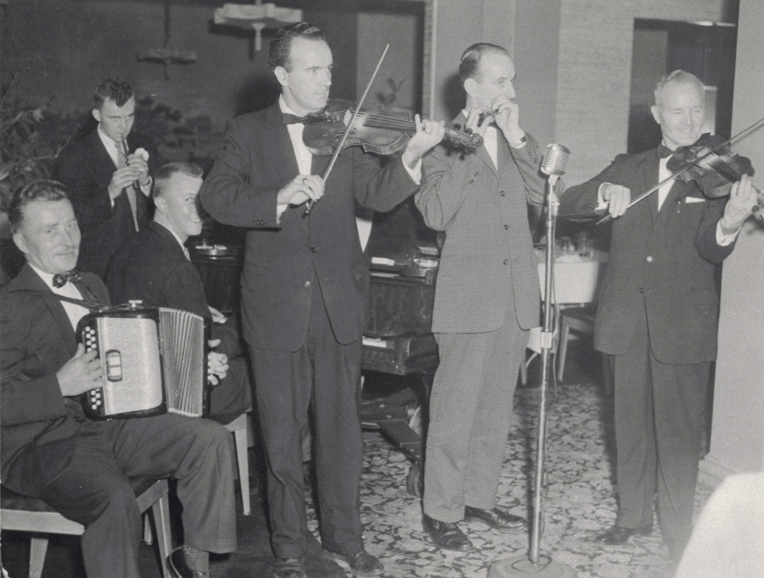 Black and white photo of six men in suits playing instruments