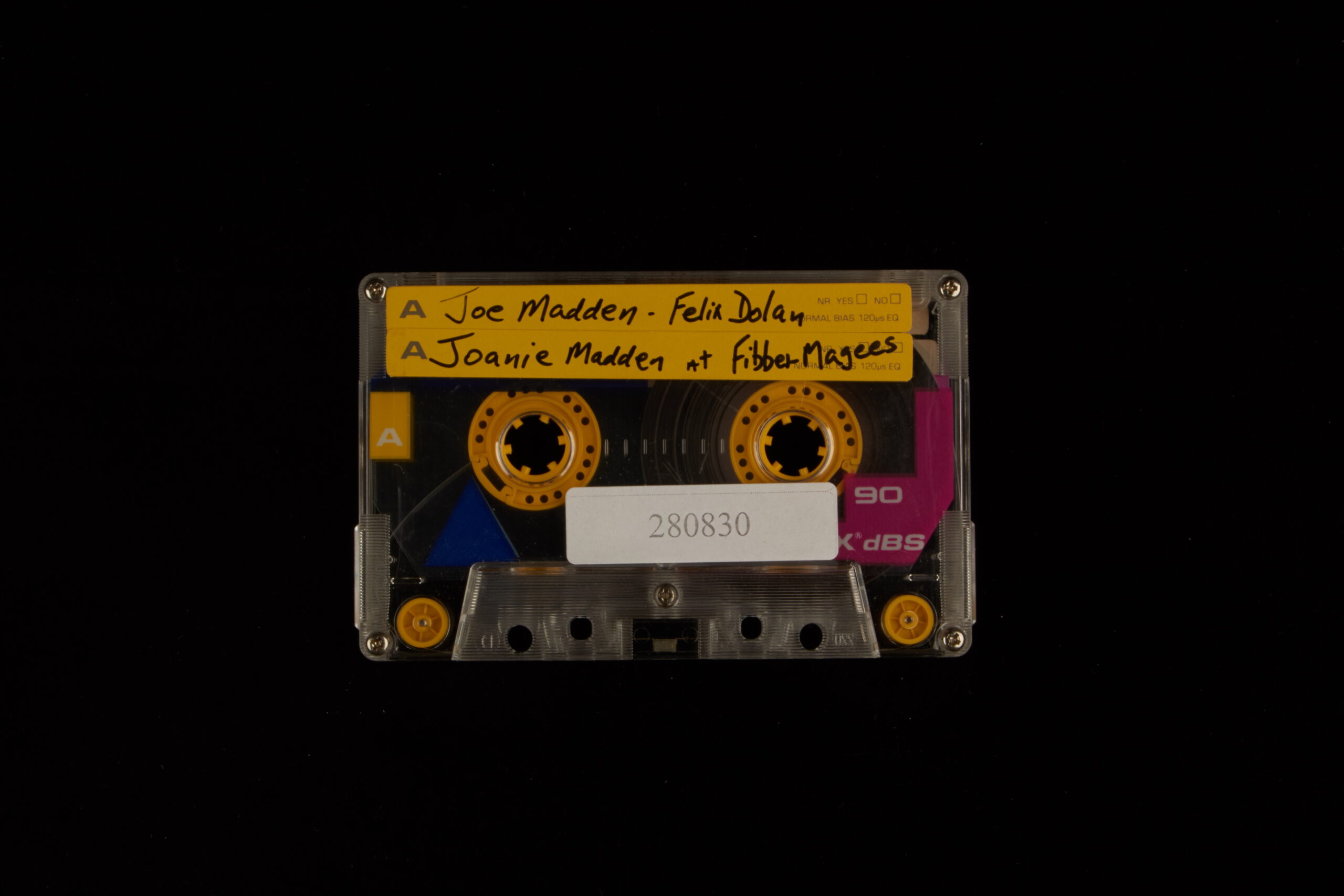 A casette tape with "Joe Madden - Felix Dolan" and "Joanie Madden at Fibber Magees" written on it in marker.