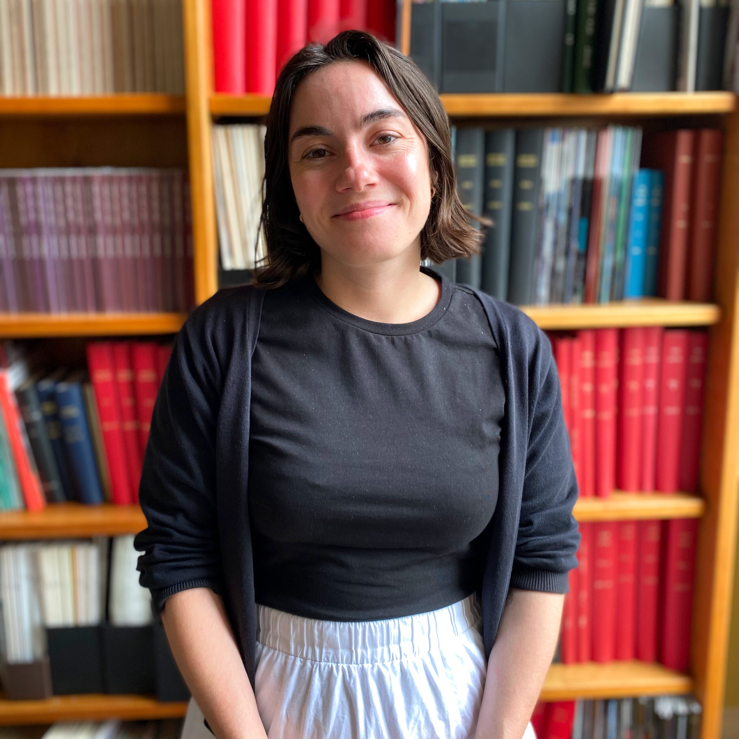 A dark-haired woman standing in front of a bookshelf