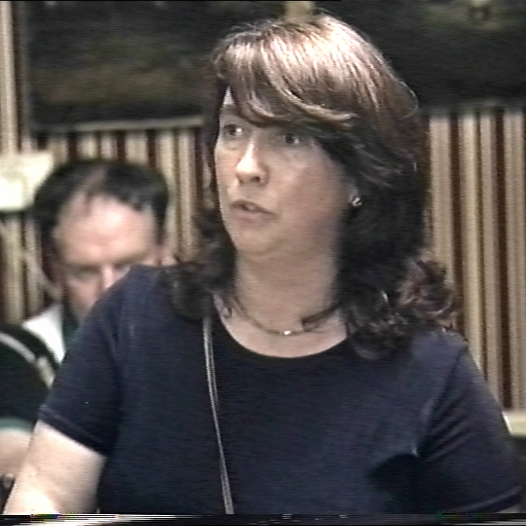 A still from an old video of a woman with dark hair singing.