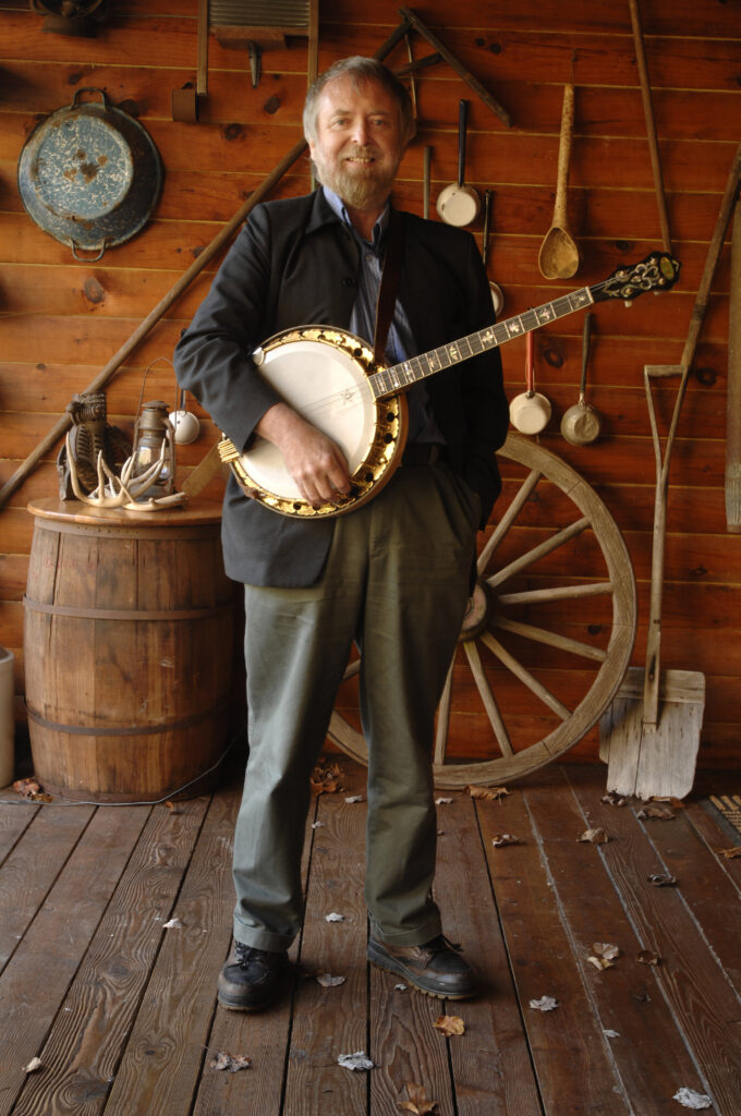 Mick Moloney standing holding banjo