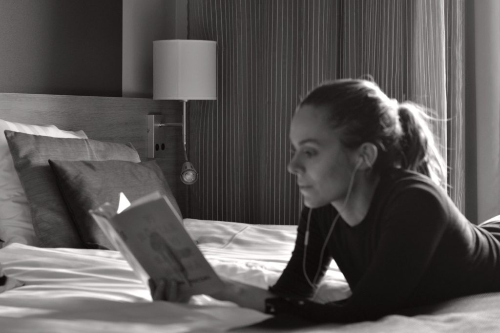 Ulrika Nettelblad ligger på en hotellsäng och läser en bok.