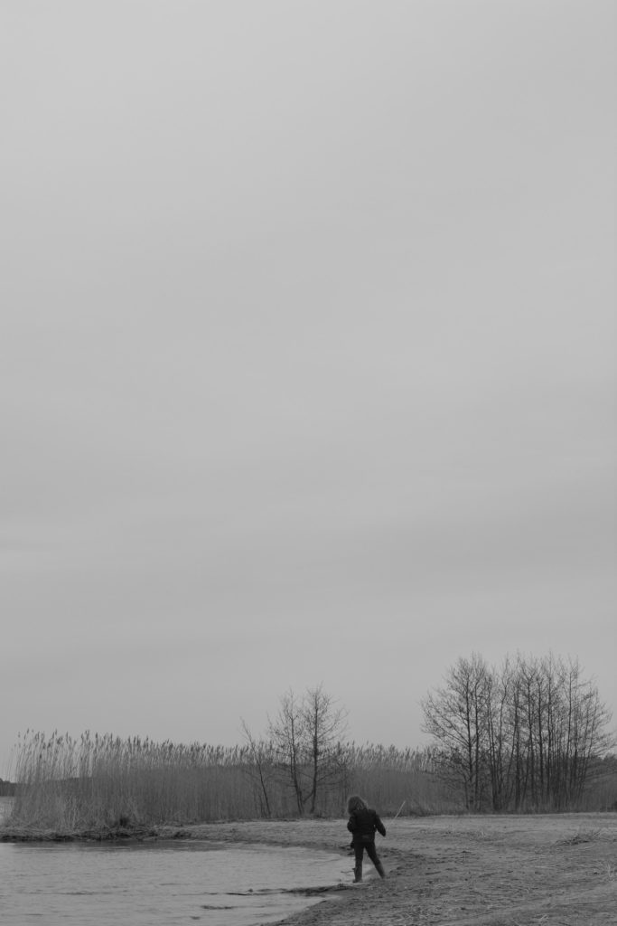 Litet barn i strandkanten. Svartvit bild.