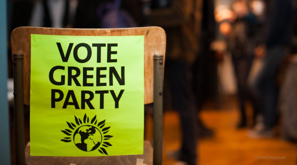A photo of the back of a chair with a poster attached reading 'vote Green Party'