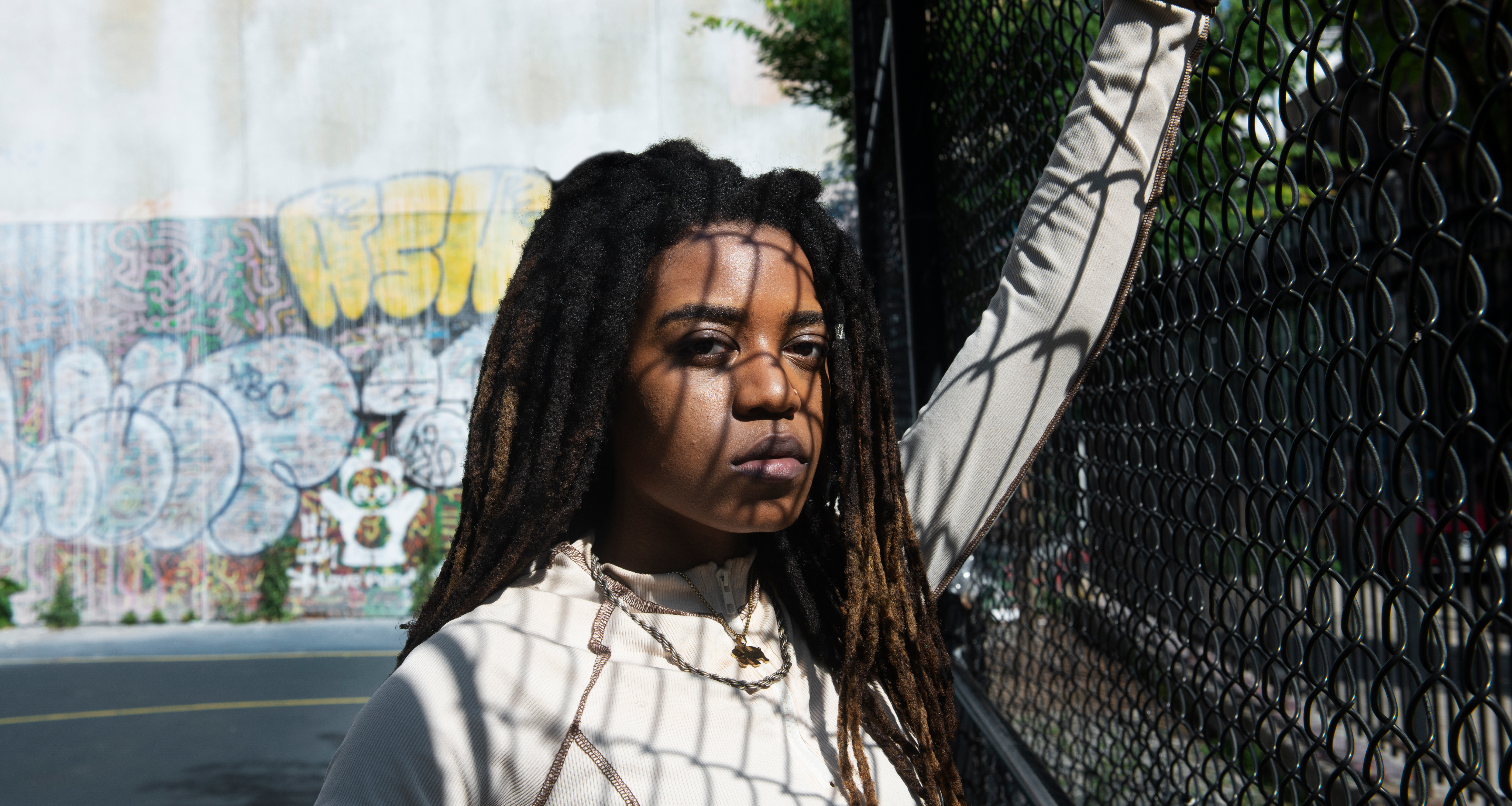 An angry-looking black woman standing in the shadow of a chain-link fence via Freepik