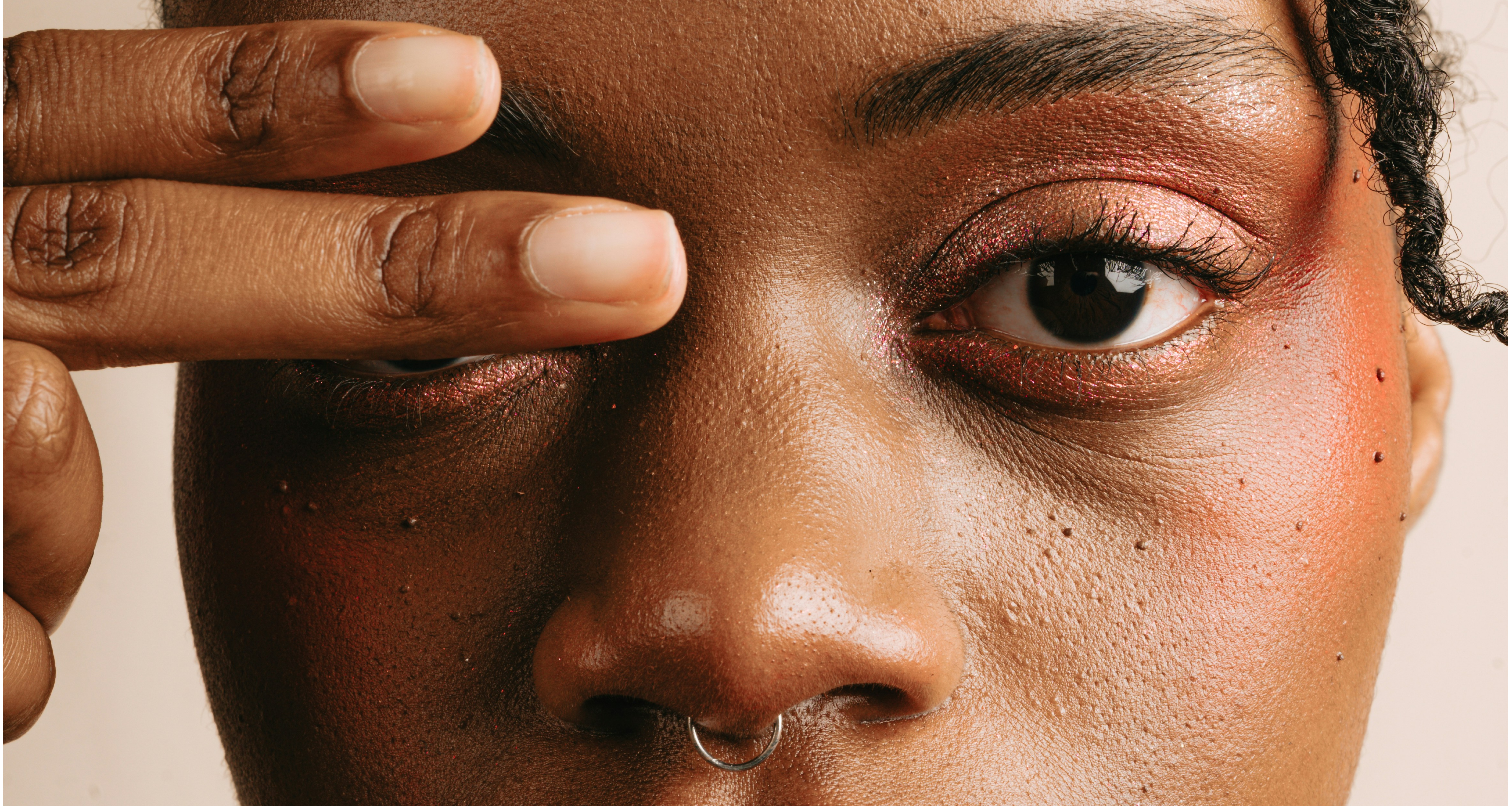 Close up shot of a black woman with two fingers over her left eye by AC via Unsplash