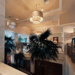 The view from the grand foyer, including a lovely staircase, royal palms, and numerous chandeliers at the Federal Palace Hotel & Casino via Marie Claire Nigeria