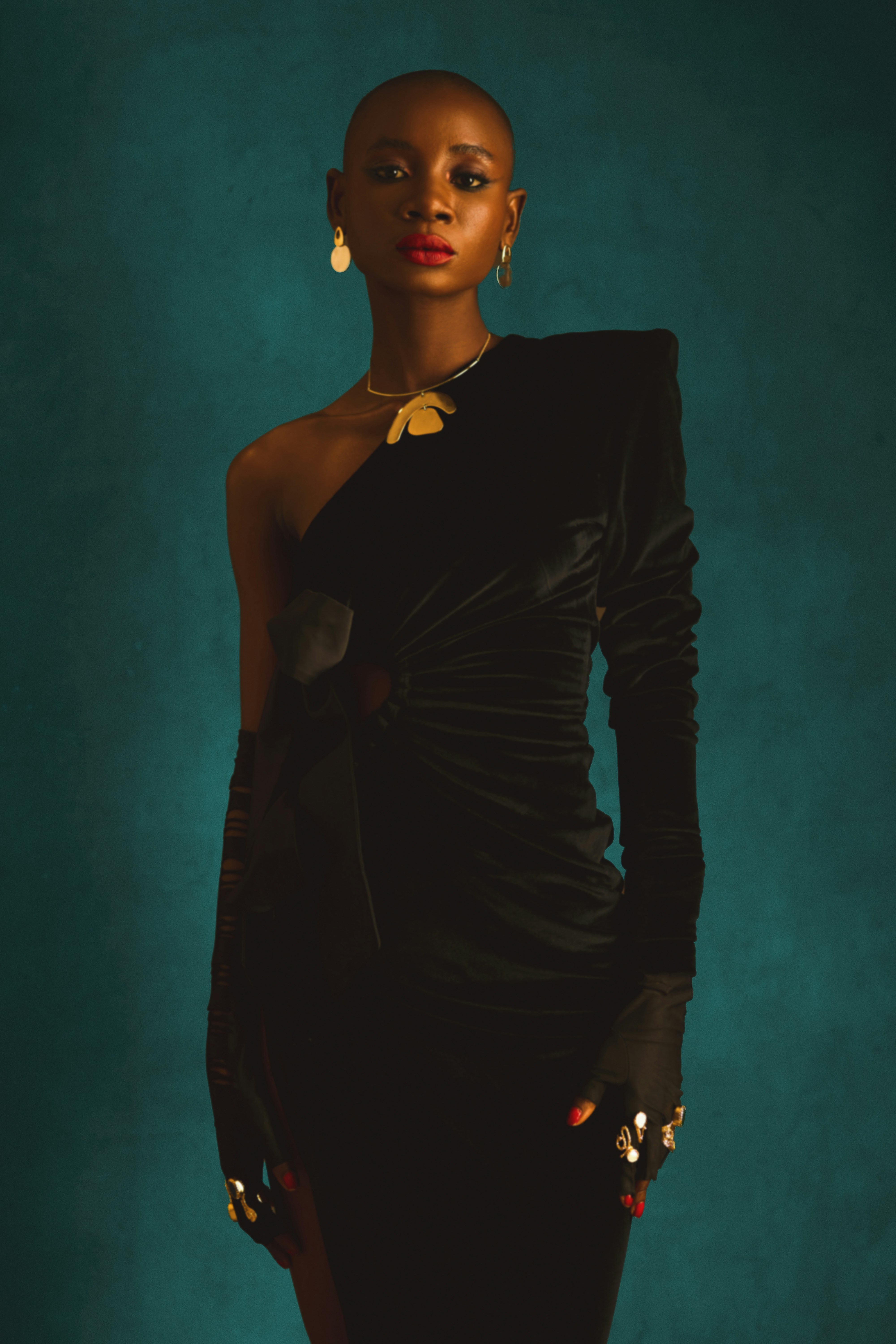 A dressed up black woman in a black dress and striking accessories by Ngozi Ejionueme via Unsplash+