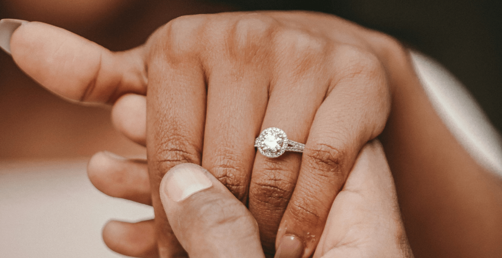 A woman's hand with a wedding ring being held by a man by Alekon Pictures via Unsplash+