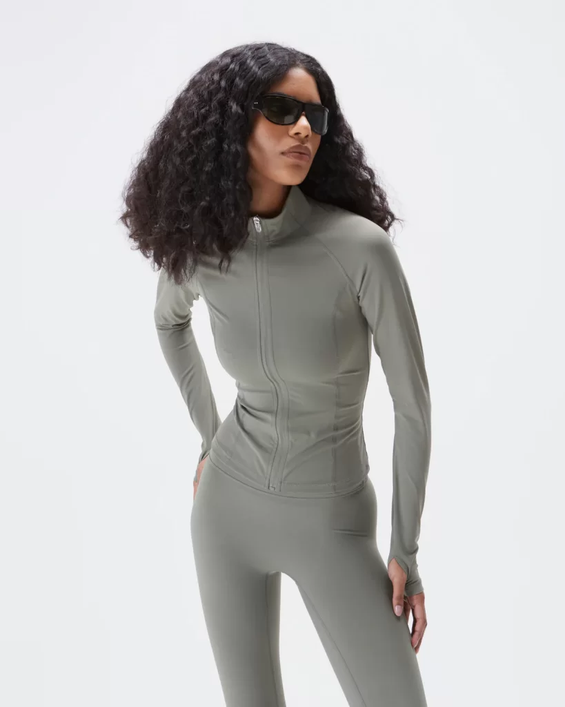 A dark-skinned model wearing Adanola Ultimate long sleeve zip up top in "Olive Green" via Adanola.com
