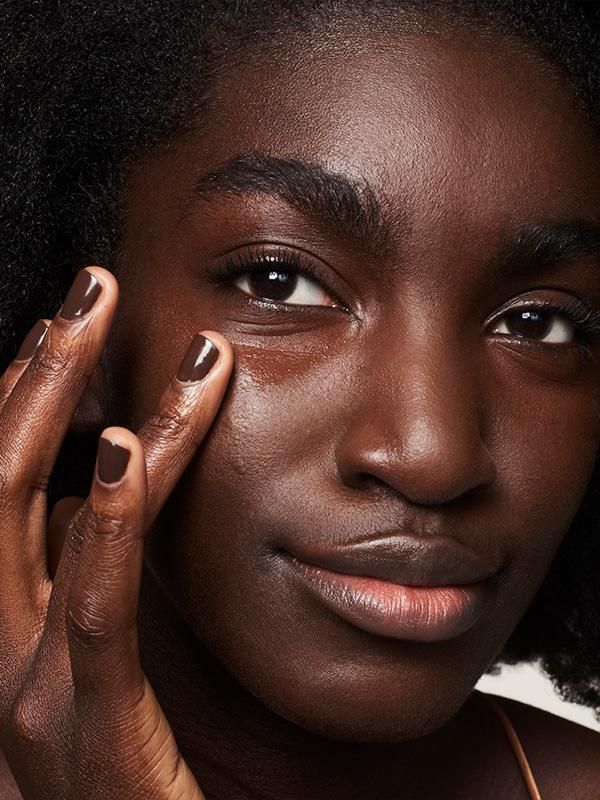 A black woman applying foundation on her face via Glossier on Pinterest