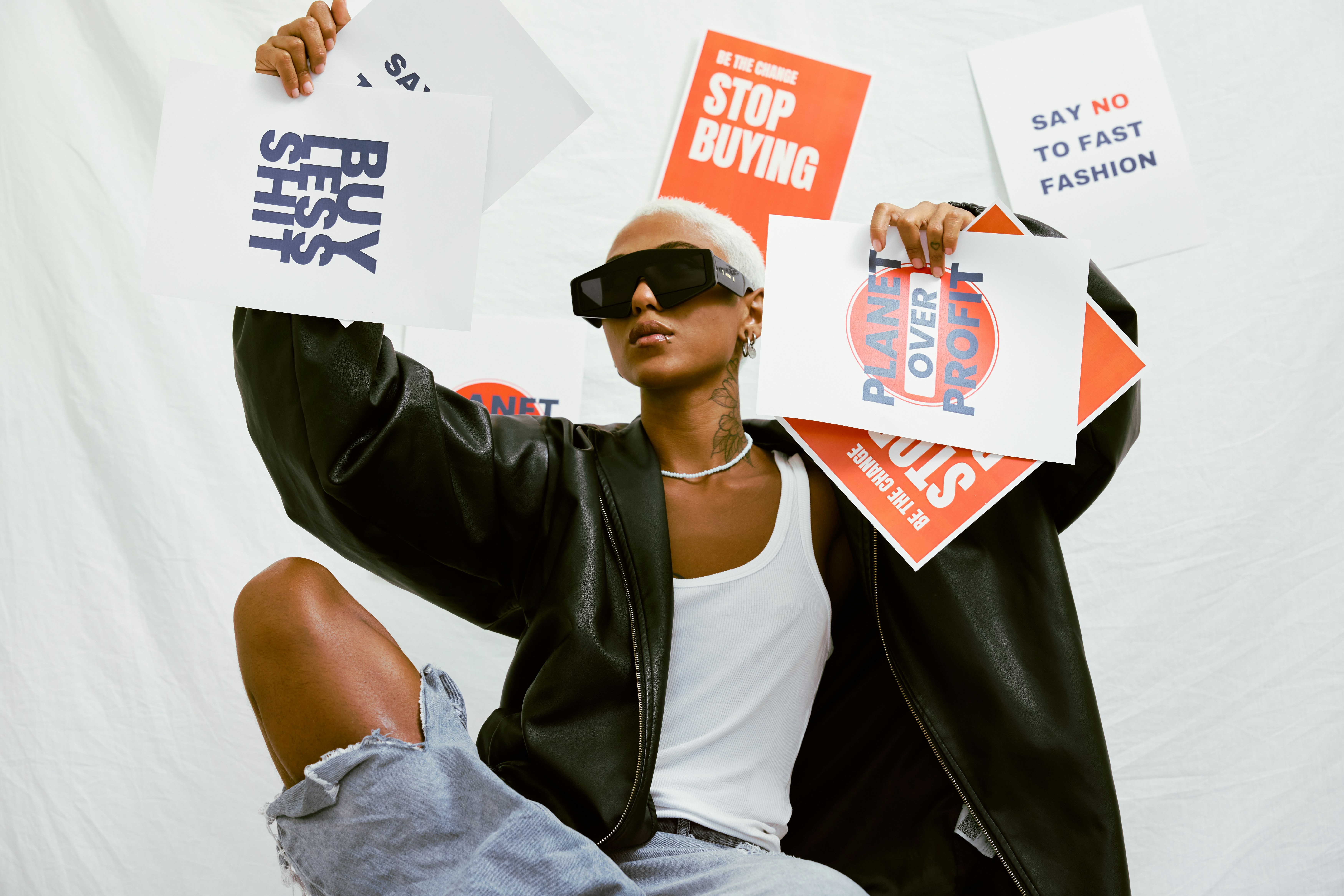 Black person holding fashion sustainability posters by Natalia Blauth via Unsplash+