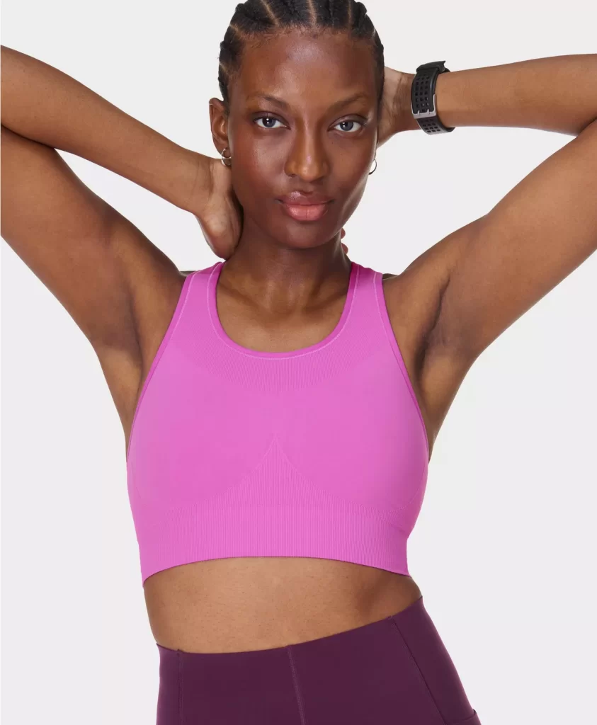 A dark-skinned model in cornrows wearing a Sweaty Betty Stamina sports bra in Allium Pink via sweatybetty.com