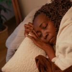 Fatigue: A black woman asleep in bed by Pablo Merchan Montes via Unsplash+