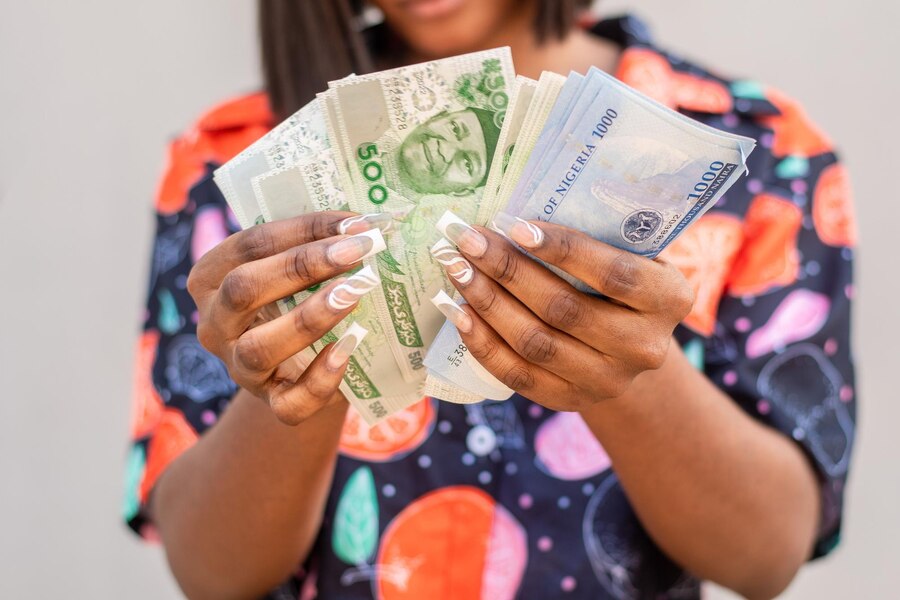 Woman holding Naira notes by Wirestock creators via Freepik