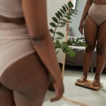 Body image; a black woman standing on a scale in front of the mirror via Getty Images on Unsplash+
