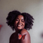 A happy black woman surrounded by butterflies by Jessica Felicio via Unsplash