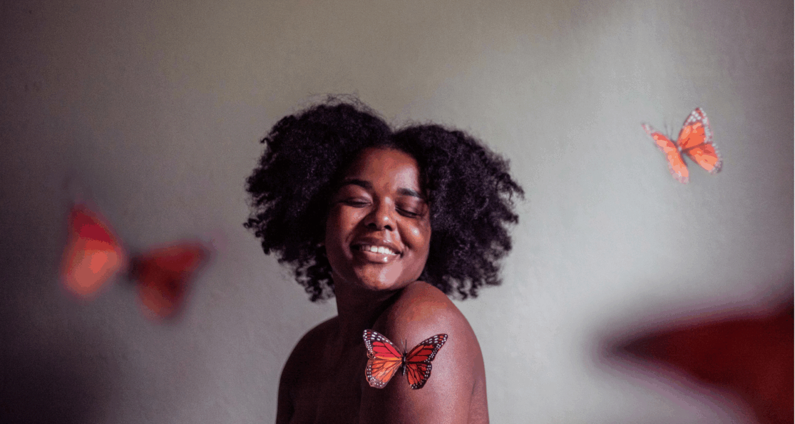 A happy black woman surrounded by butterflies by Jessica Felicio via Unsplash