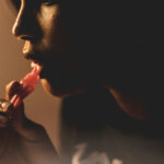 Black woman applying lip gloss via unsplash
