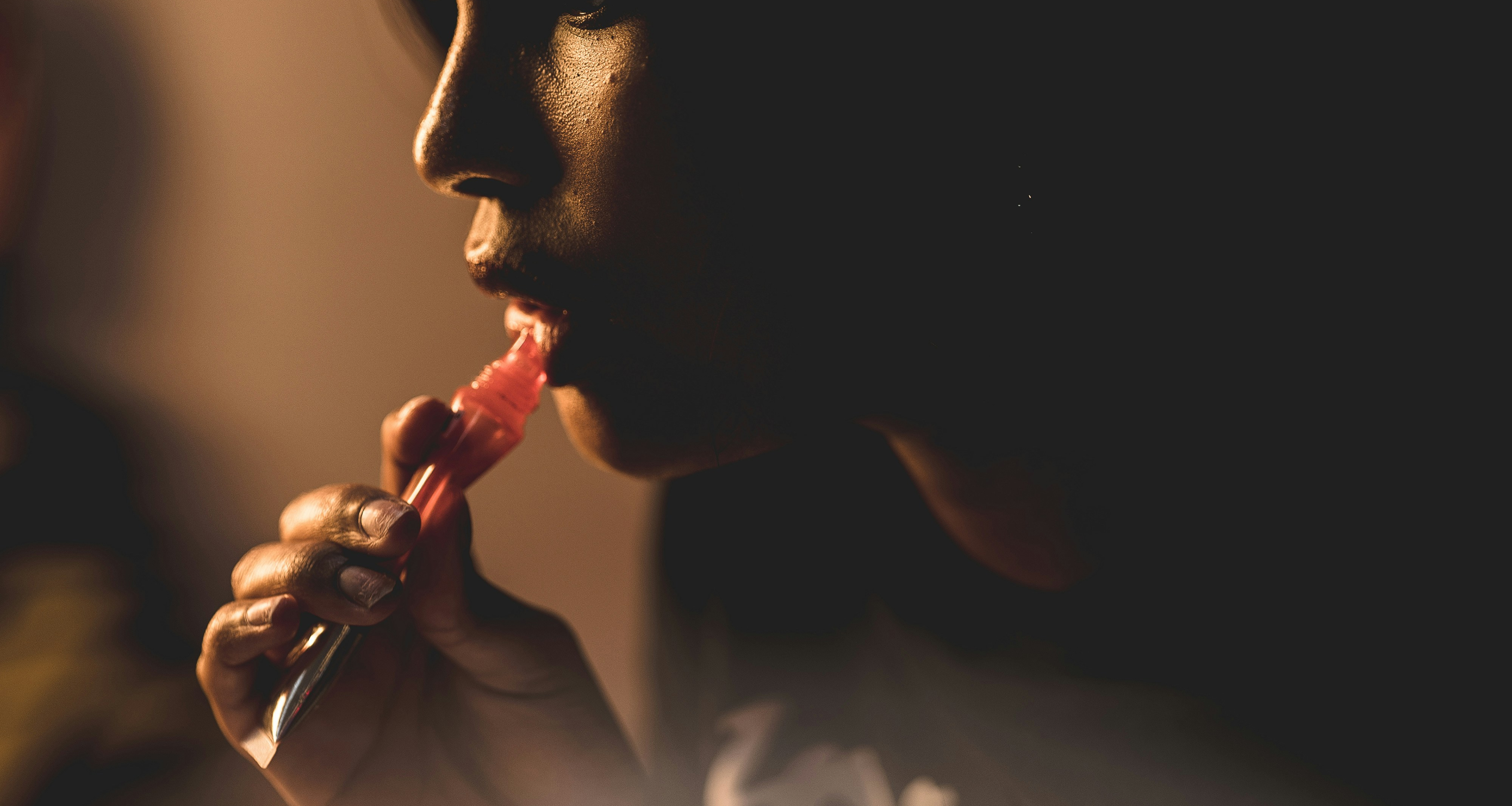 Black woman applying lip gloss via unsplash