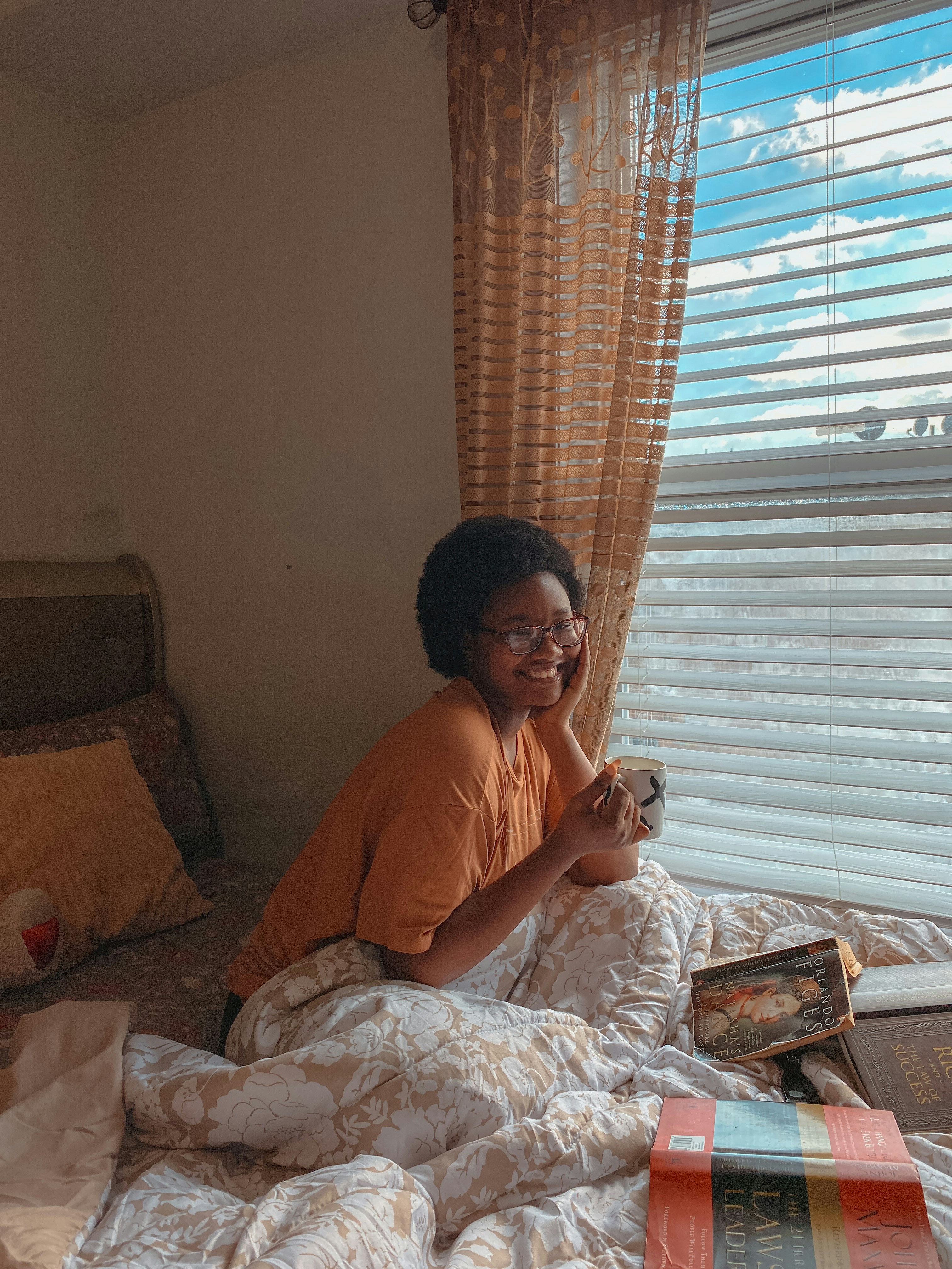 A black woman smiling and sitting up in bed by Obinna Valentine via Unsplash