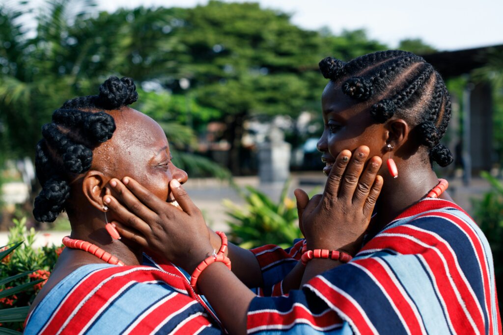 Black woman as divine; Two women with native hairstyles touching each other’s faces tenderly