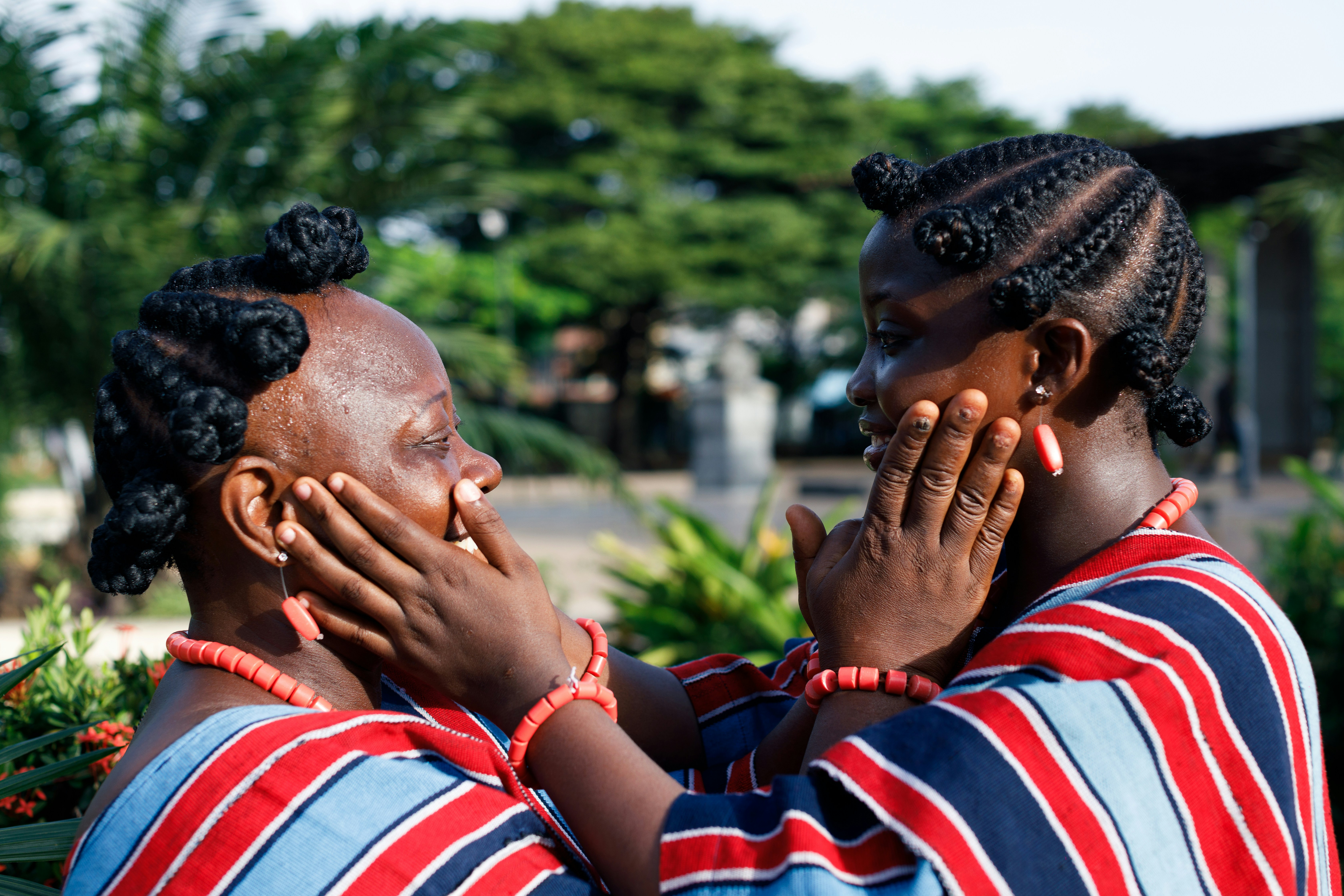 Two women with native hairstyles touching each other’s faces tenderly