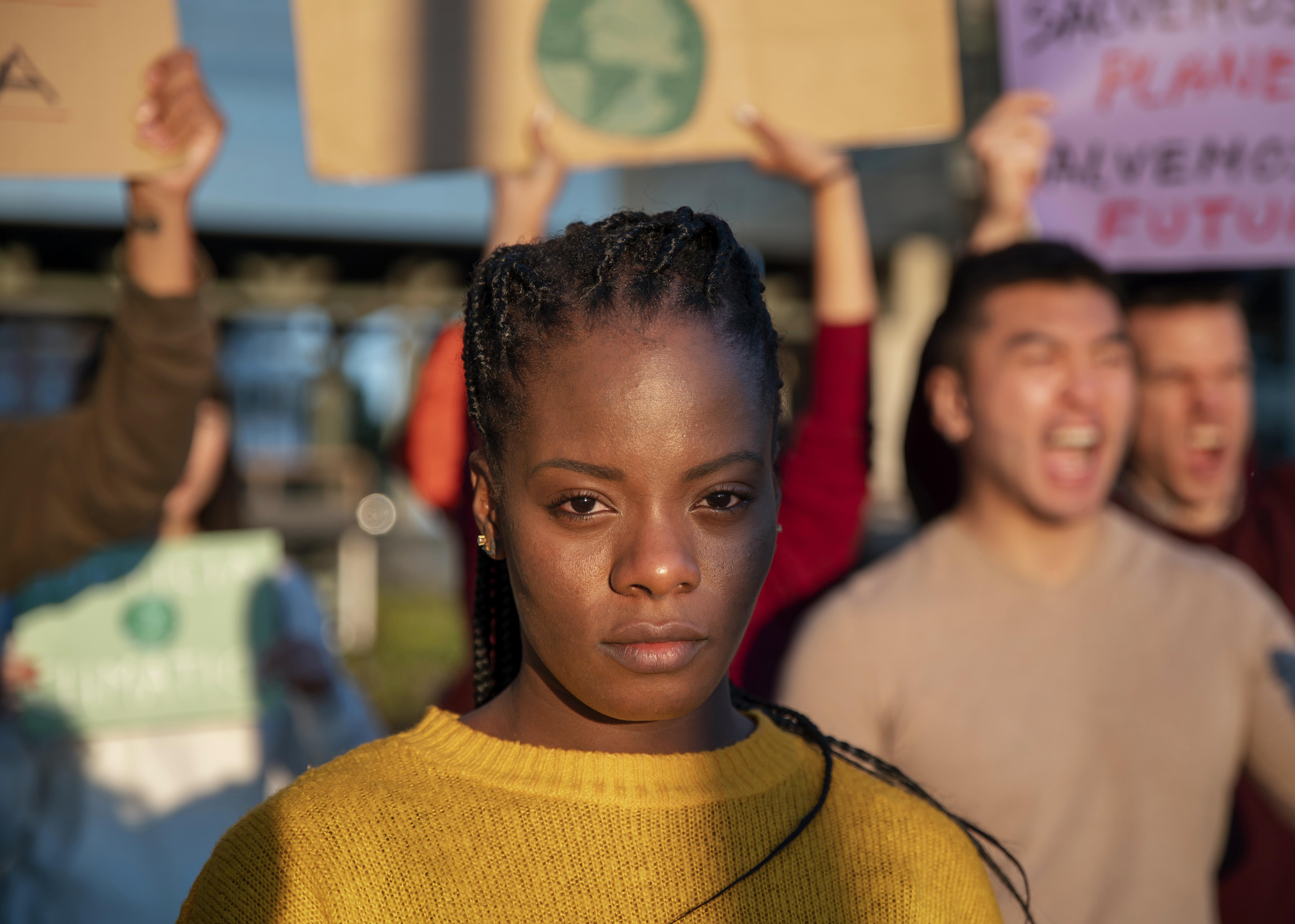 A close up shot of a sober-looking black millennial woman at a protest via Freepik