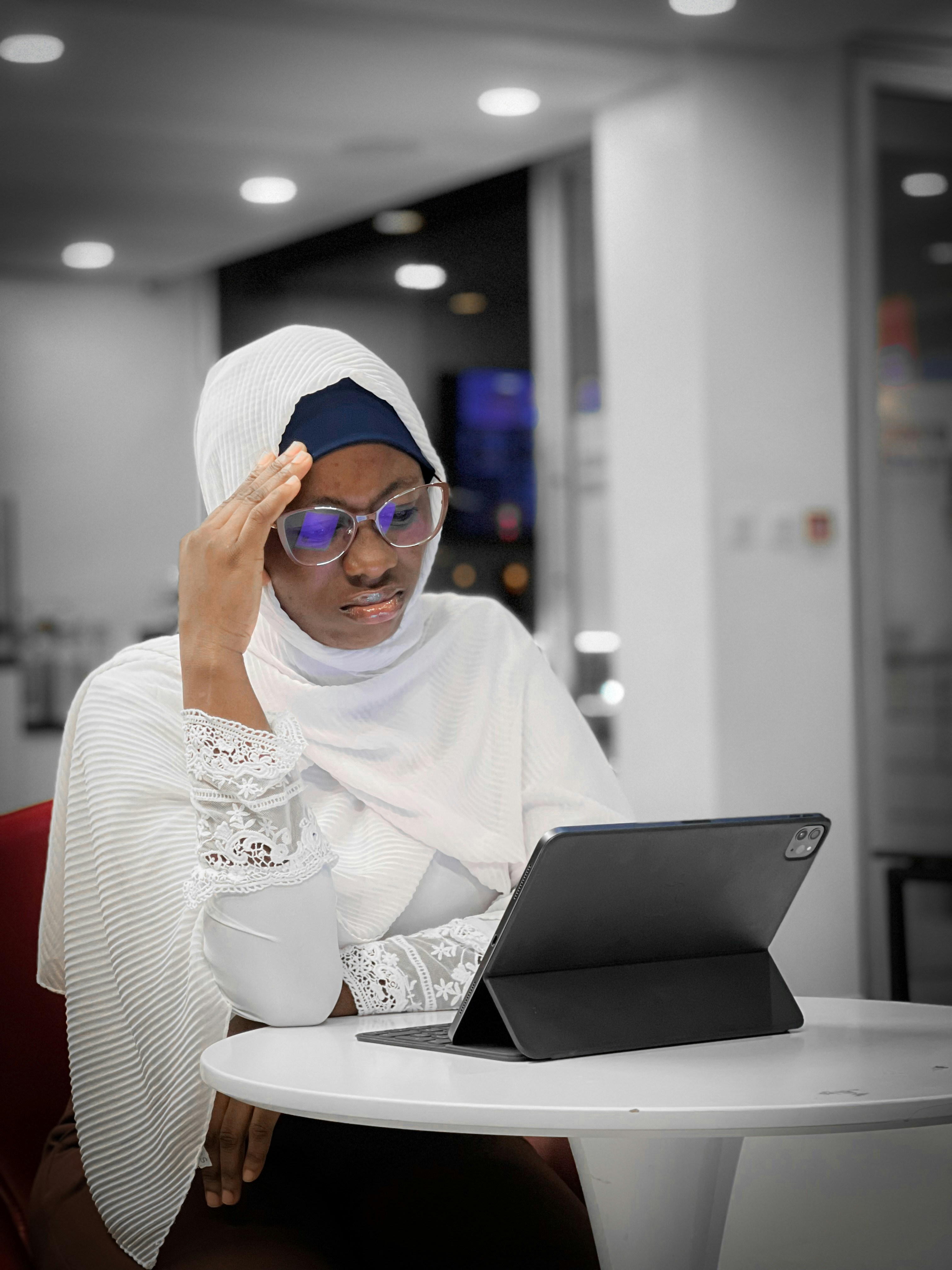 Work stressors; A black woman hijabi sitting in front of an iPad, looking stressed by Francis Odeyemi via Unsplash