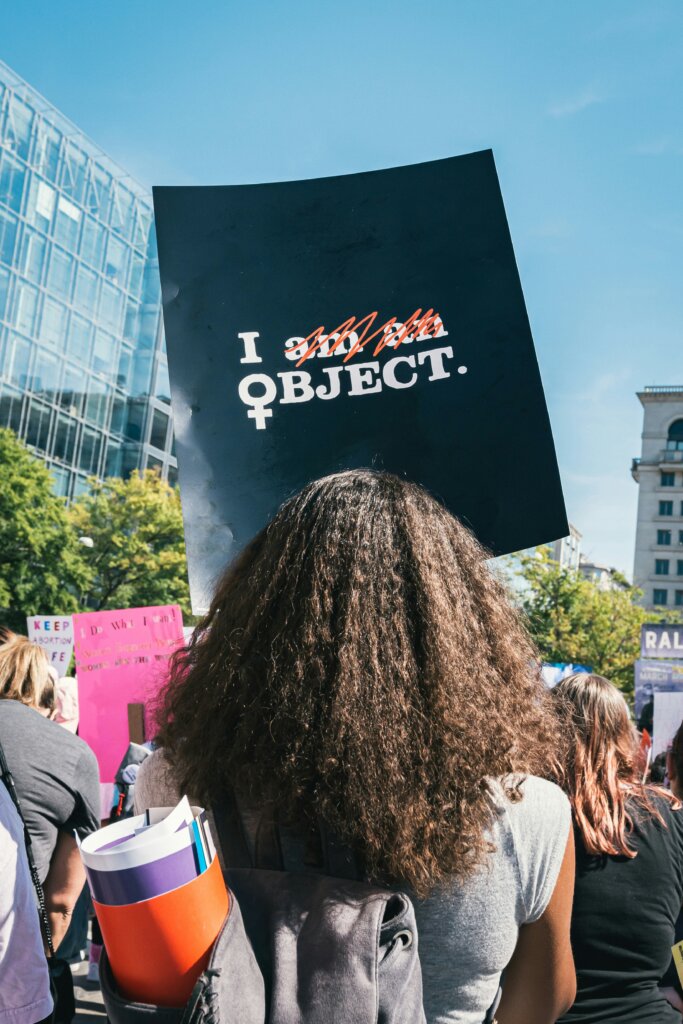 A Black woman holding a sign that says “I Object” at a rally