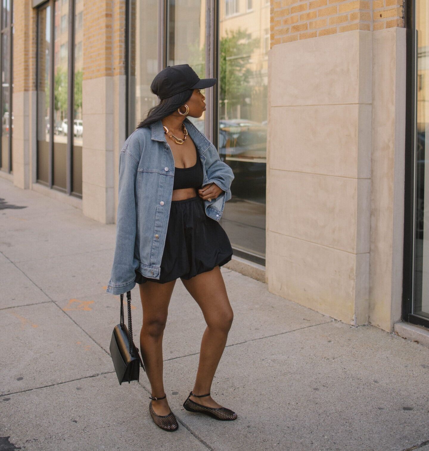 A black woman wearing a denim jacket, bubble skirt and mesh ballet flats via stealthelook.com