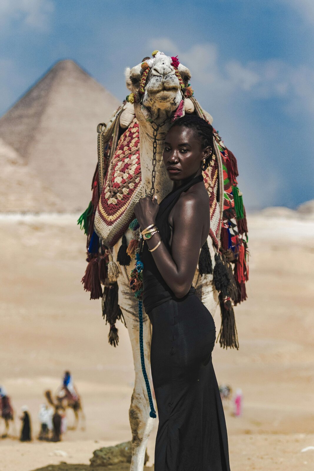 Black woman holding the reins of a camel in a desert by Lisa Marie via Unsplash