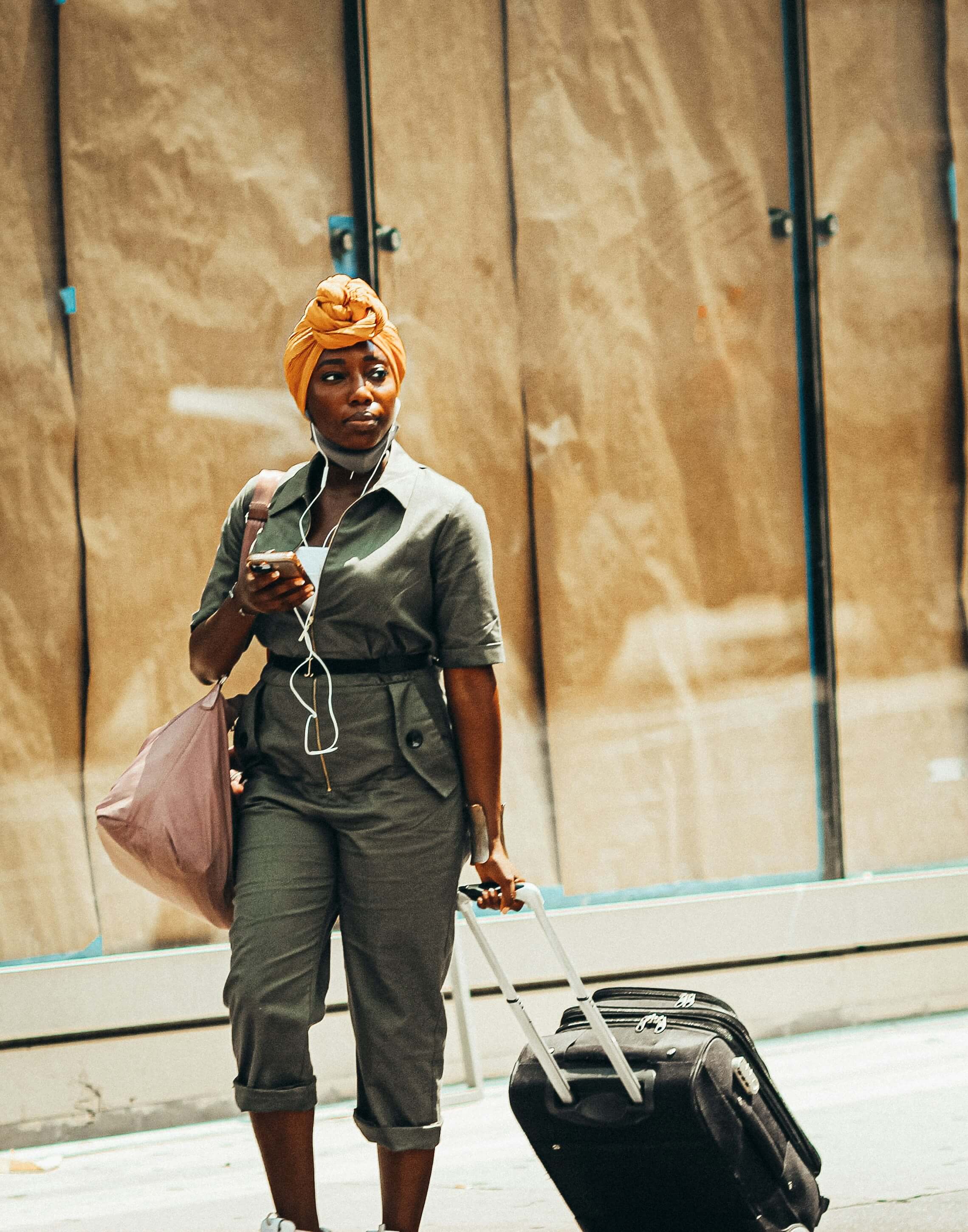 Black woman holding a suitcase by Jon Tyson via Unsplash