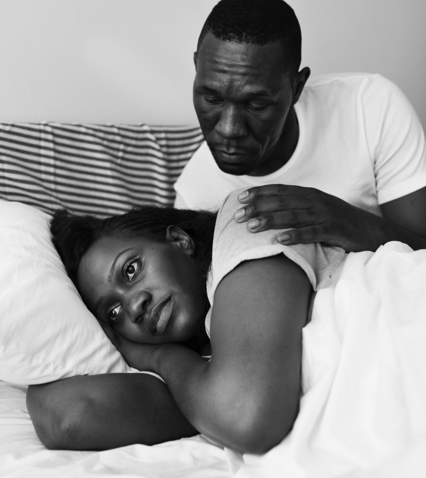 Black couple laying in bed with the woman turned away from her partner for save your relationship piece.