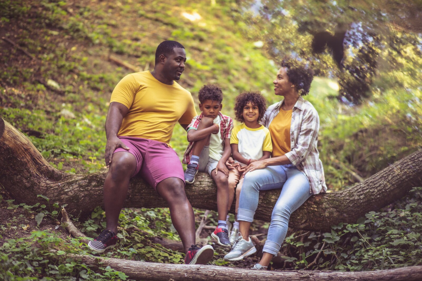 Black family sitting on a tree branch in a forest by Getty Images via Unsplash