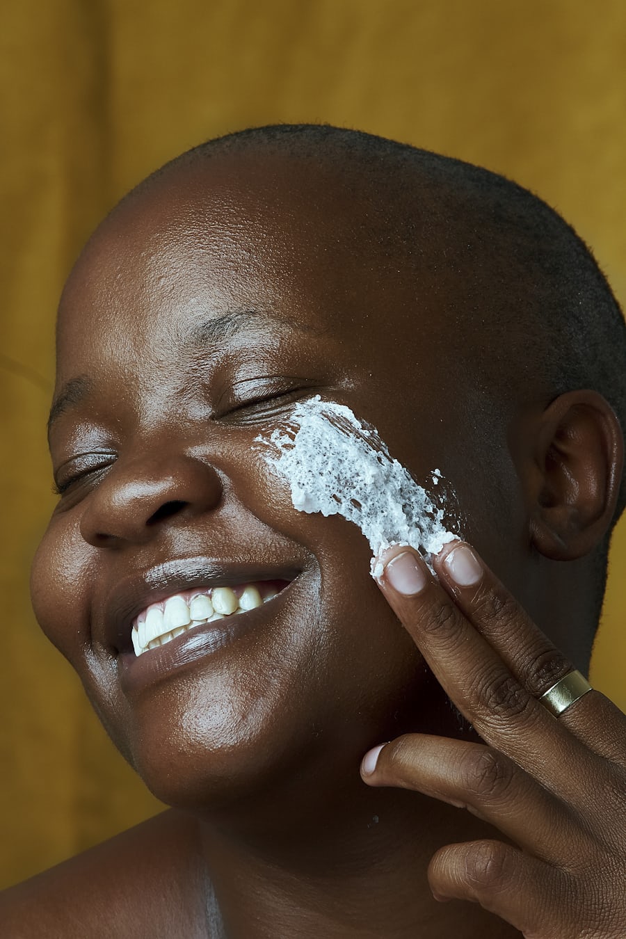 Black woman applying a cream on her face by Ben Masora via Unsplash+