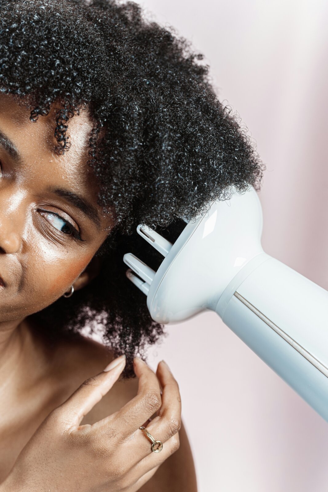 Post-trip skin reset - Black woman blow drying her natural hair by A.C. via Unsplash