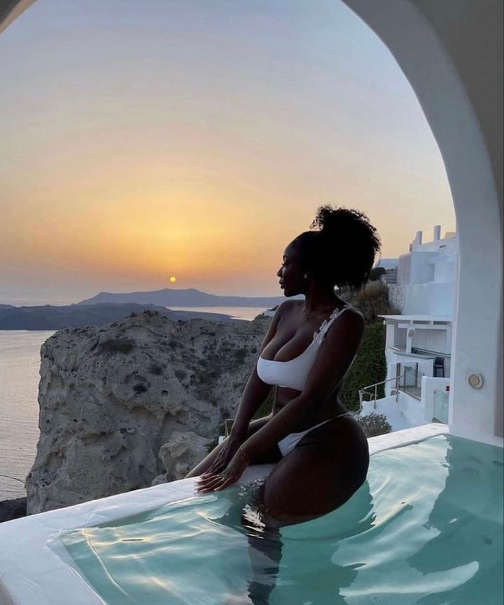 Black woman sitting in a pool at sunset in Santorini, Greece via @Shani Jamilah on Instagram