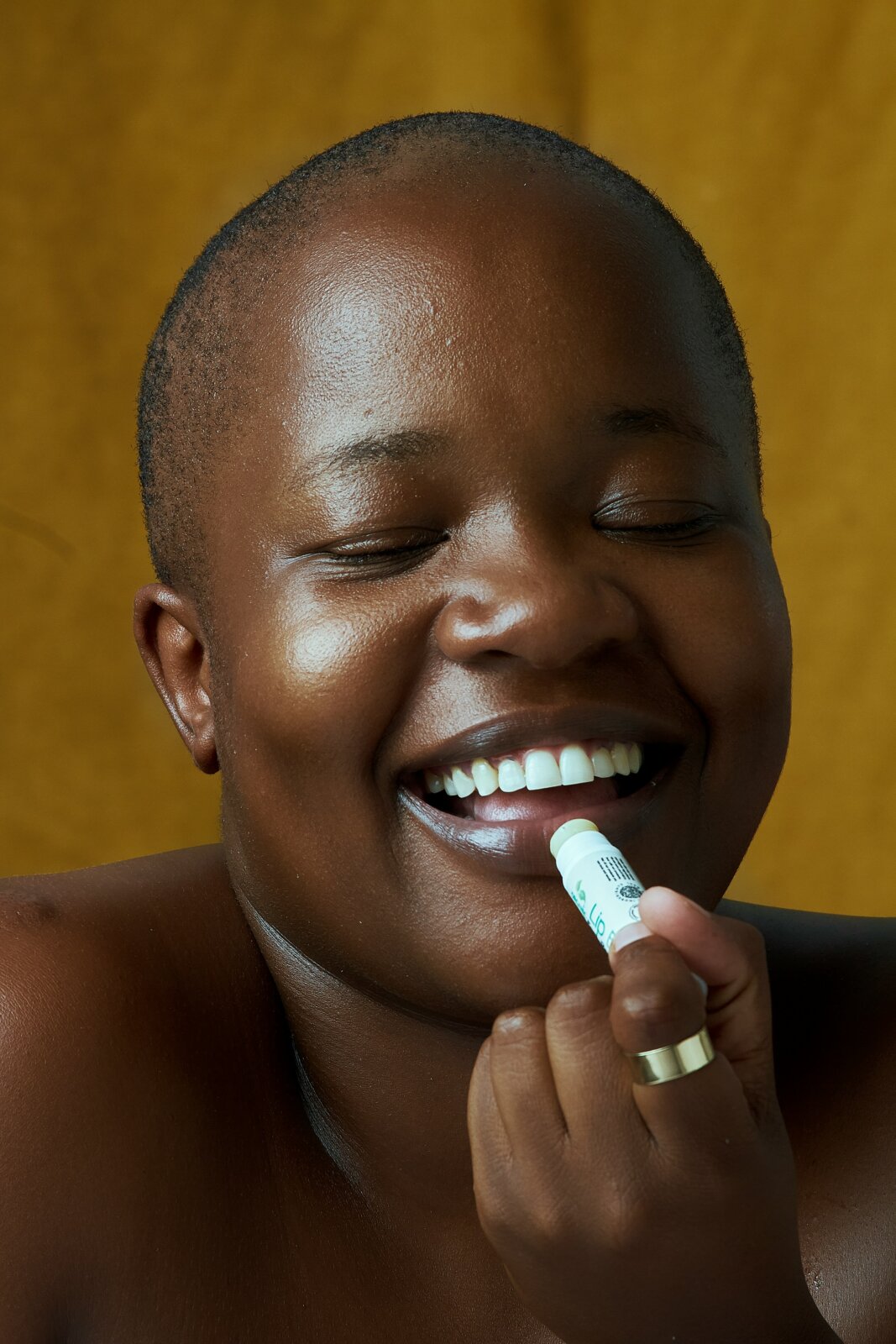 A woman smiling while applying lip balm by Ben Masora via Unsplash
