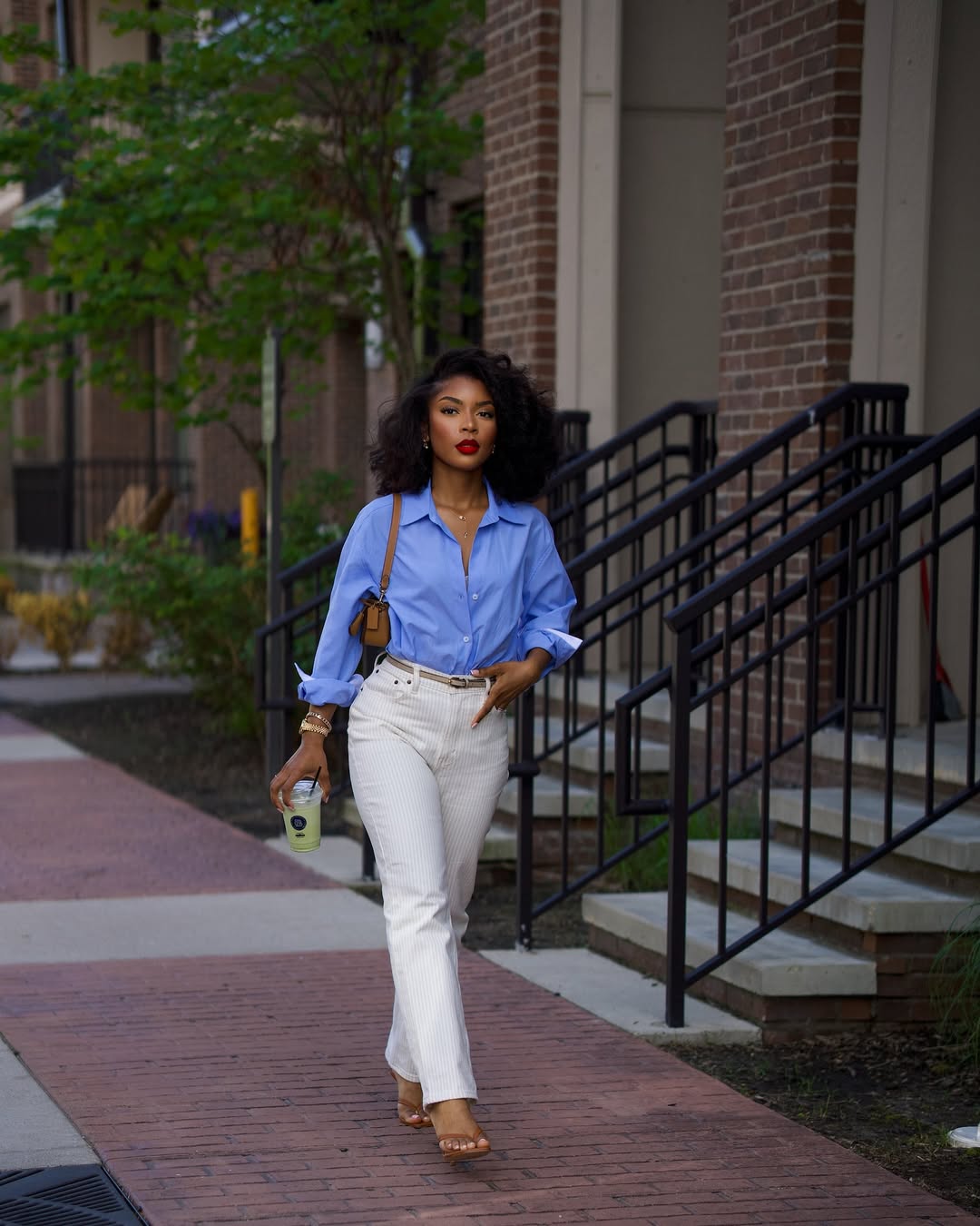 Desi Rich in blue button-down shirt and cream trousers via @iammdesii on Instagram
