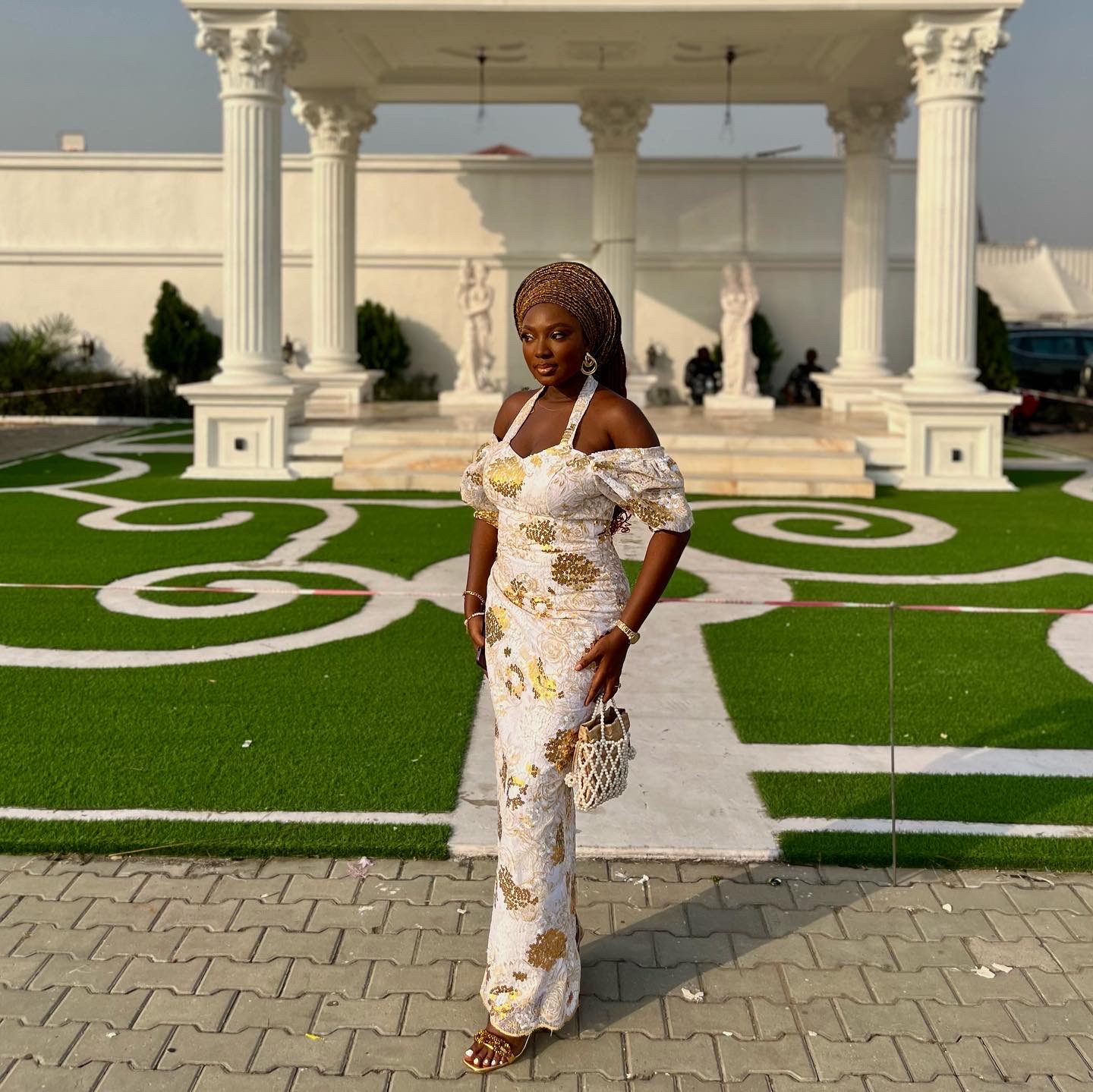 Wumi Tuase-Fosudo in a cream and gold lace asoebi dress and beaded bag