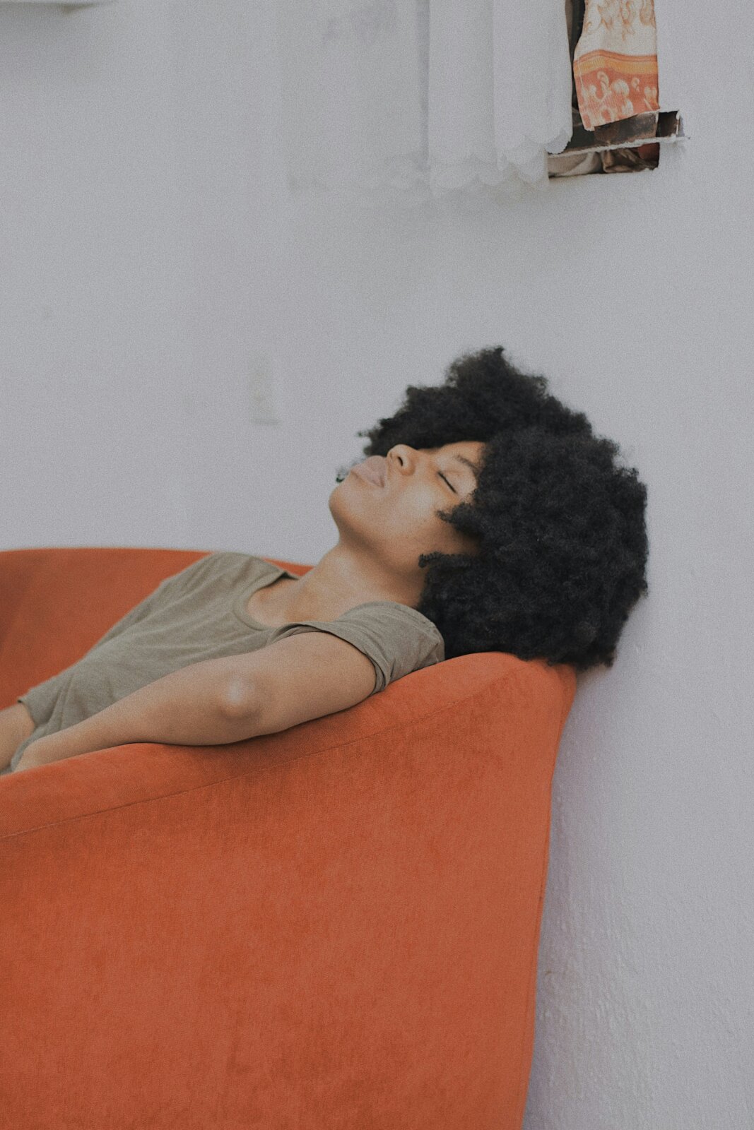 Black woman sitting in a chair with her eyes closed by Baptista Ime James via Unsplash