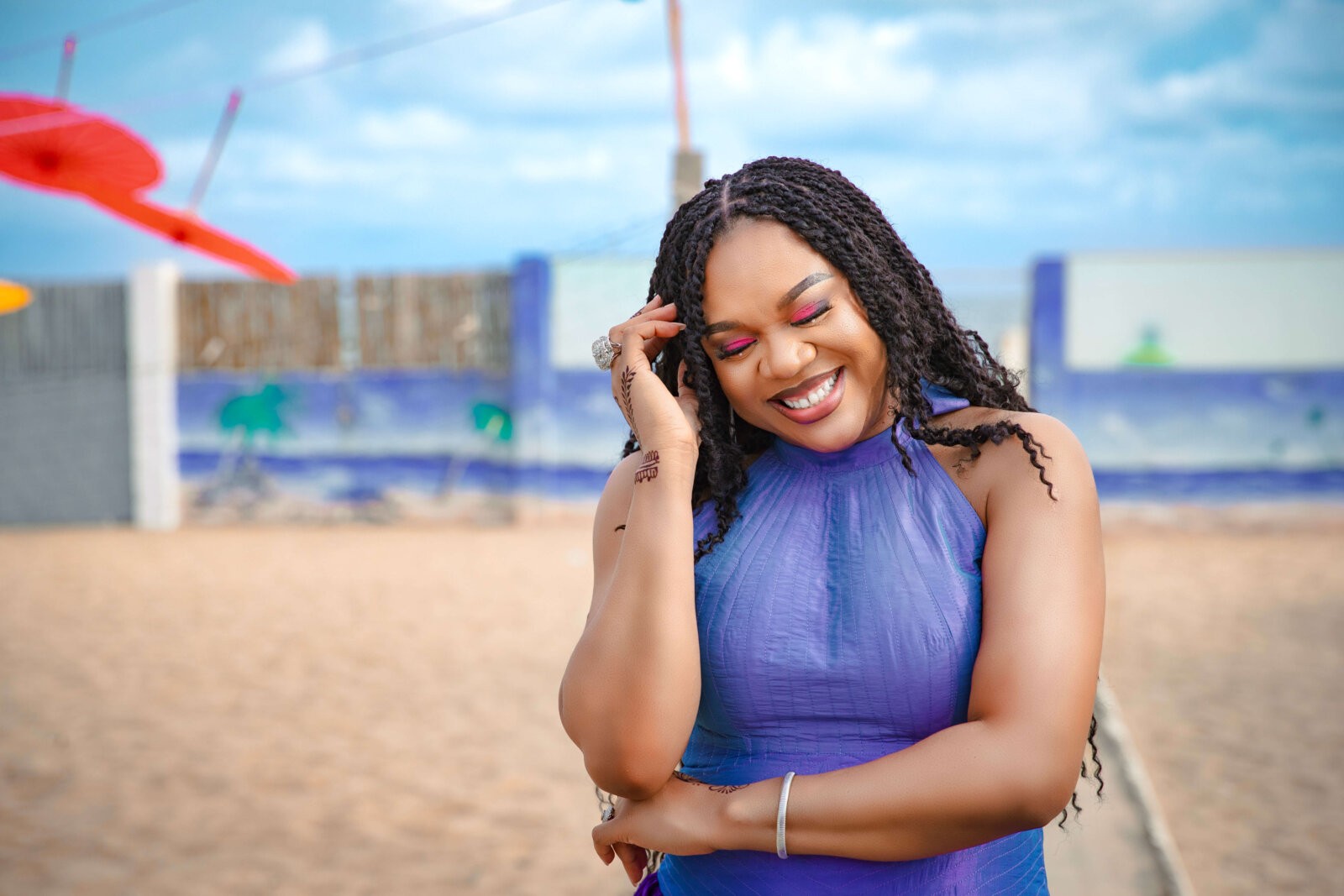 Stella Damasus posing in a purple dress while smiling widely by IzzyBelle Images