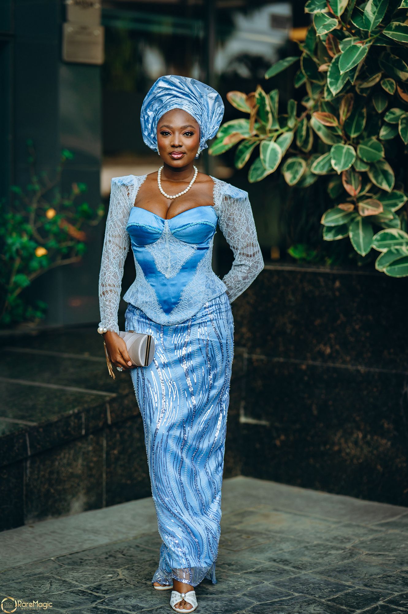 Wumi Tuase-Fosudo in a blue lace two-piece asoebi outfit and silver clutch purse