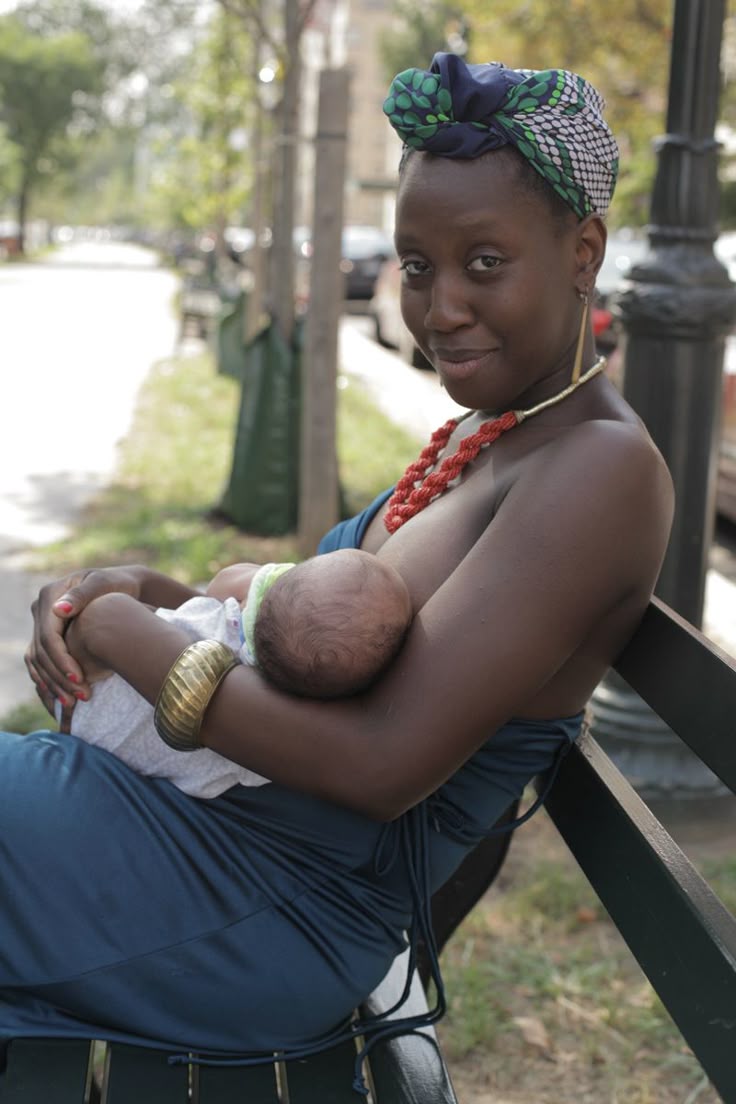 Black woman breastfeeding in public on a park bench via Pinterest.