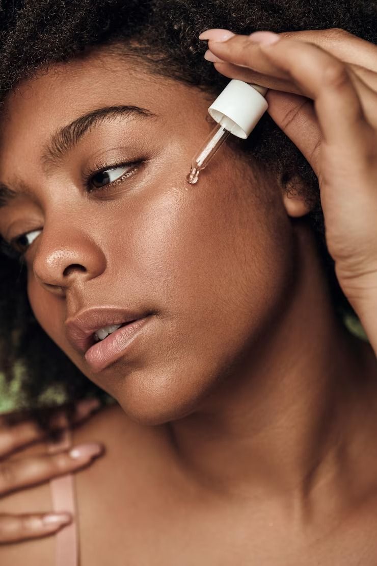 Niacinamide- Black woman applying a serum to her face via Freepik