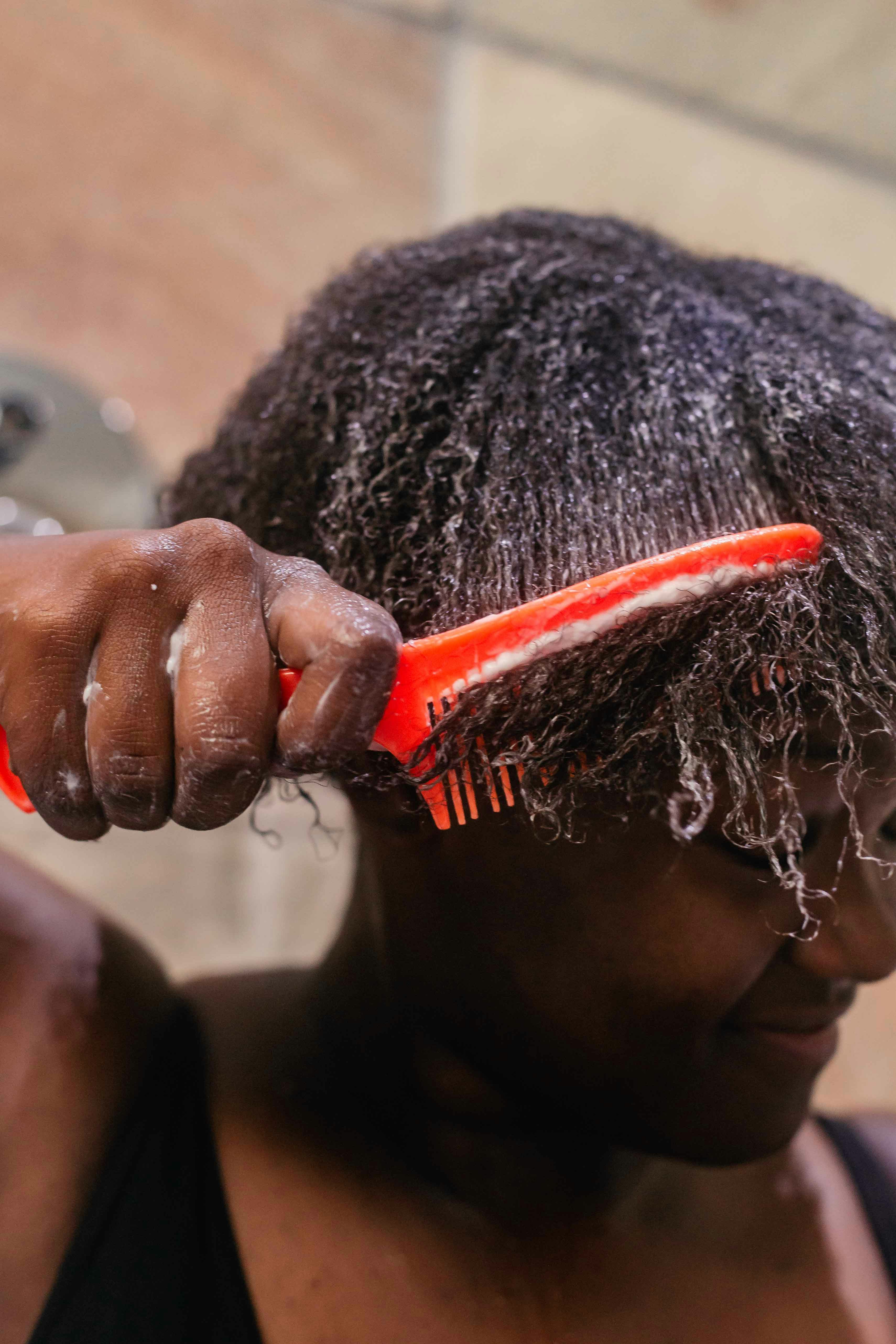 Hair mask; Close up shot of a black woman combing through her 4c curls with a red comb by Sincerely media via Unsplash